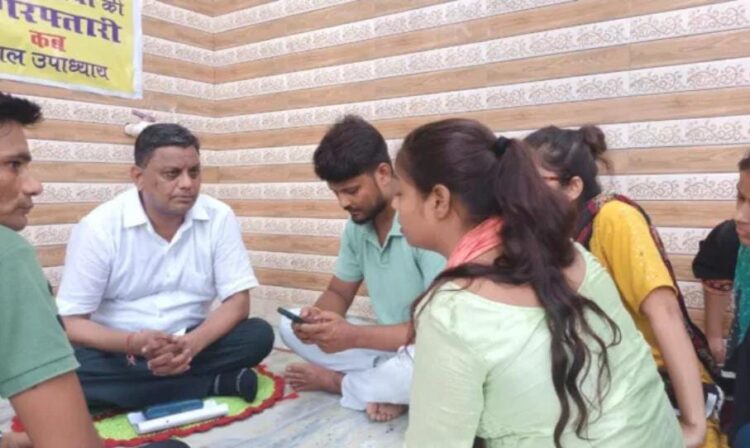 शाहगंज में भोले बाबा के घर के बाहर धरने पर बैठा युवक